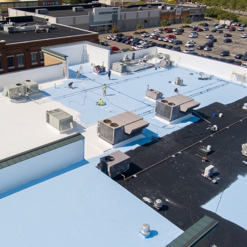 Crew installing commercial roofing membrane on large industrial facility